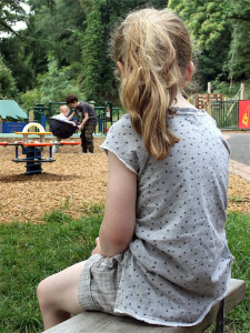 Divorce and special needs children: picture of back of girl sitting alone in playground