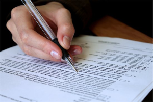 spousal support: photo of person's hand holding a pen and filing out documents