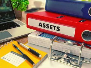 Mediation Financial Issues - photo of notebooks labeled "assets", eyeglasses, pens, and laptop on a table