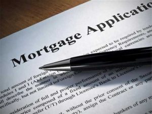 Photo of pen lying on top of mortgage application illustrating need to refinance after divorce