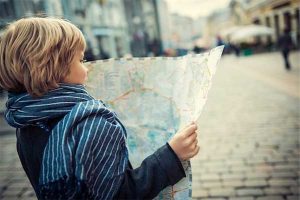 Photo of a young boy looking at a map to navigate a city street as an example of free-range parenting