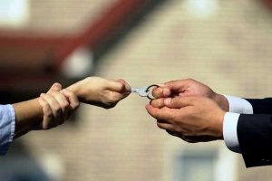 Property distribution; pair of woman's hands and man's hands tugging on a house key