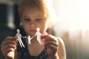 Young child with paper doll cutout of parents and child depicting parallel parenting arrangement after divorce