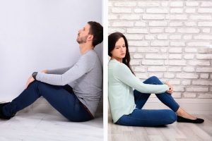 Couple sitting back-to-back with wall separating them as they deal with post-divorce conflicts