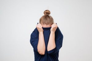 Woman hiding head in navy sweatshirt symbolizing fears associated with divorce